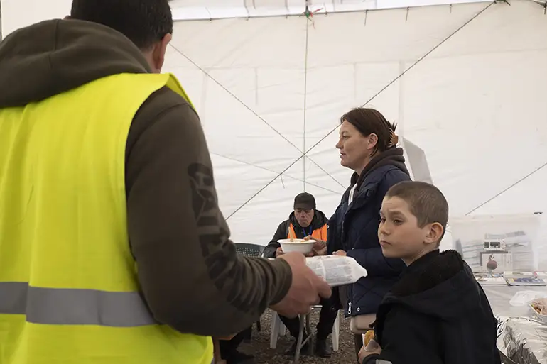 Dans la tente-refectoire de la zone de transit bénévoles et réfugiés se cotoient pour manger et se mettre à l'abri du vent.